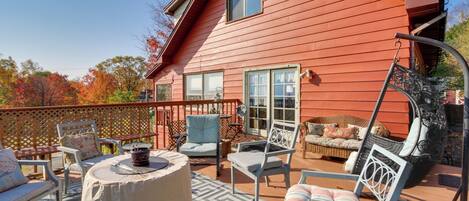 A red wooden house with a patio area featuring outdoor furniture and a swing chair.