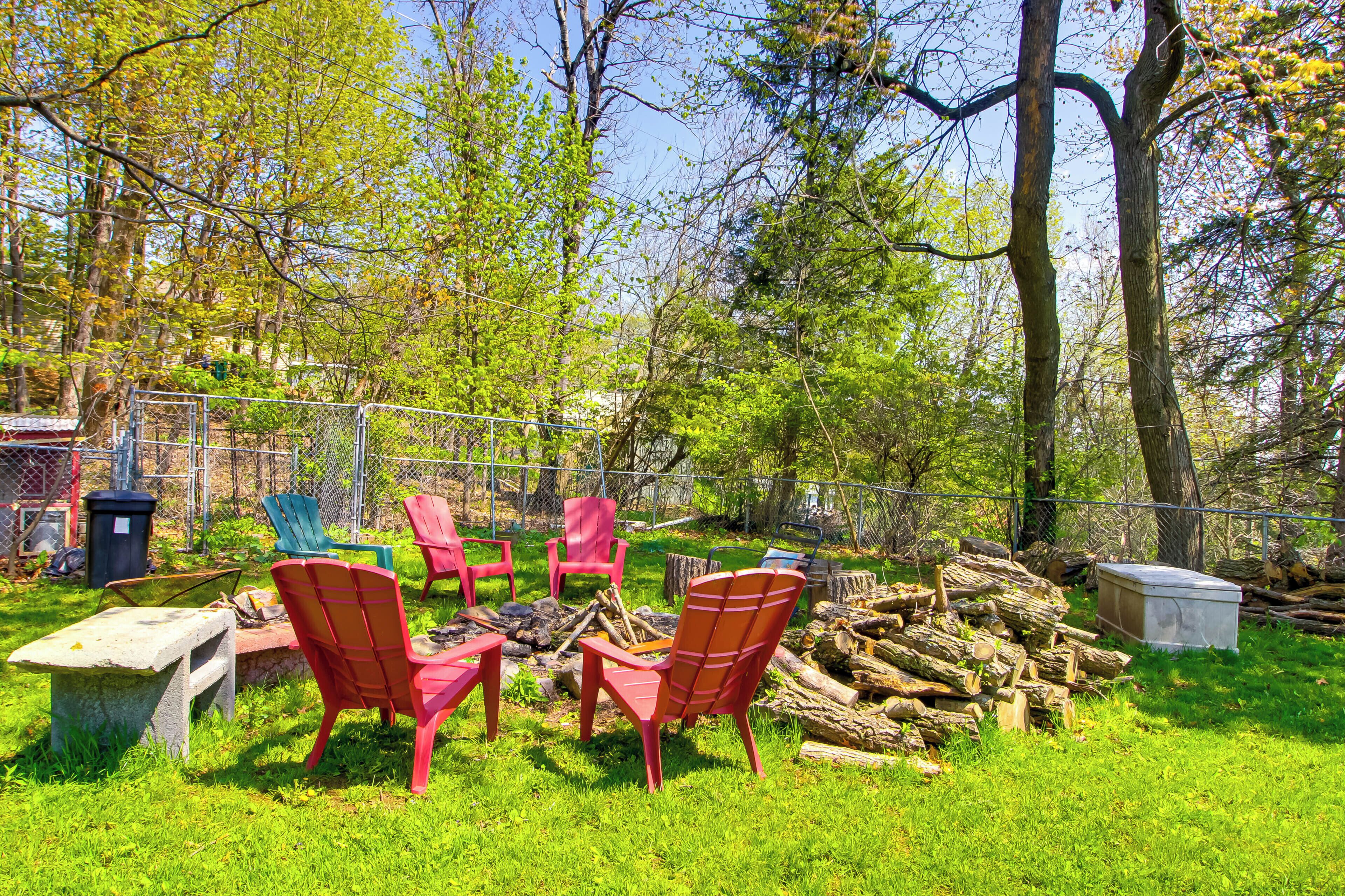 A backyard with outdoor seating, a fire pit, and a pile of firewood.