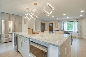 A modern kitchen with a marble countertop, stainless steel appliances, and geometric pendant lights. - Spacious Riverfront Delaware Home w/ Views (Delaware)