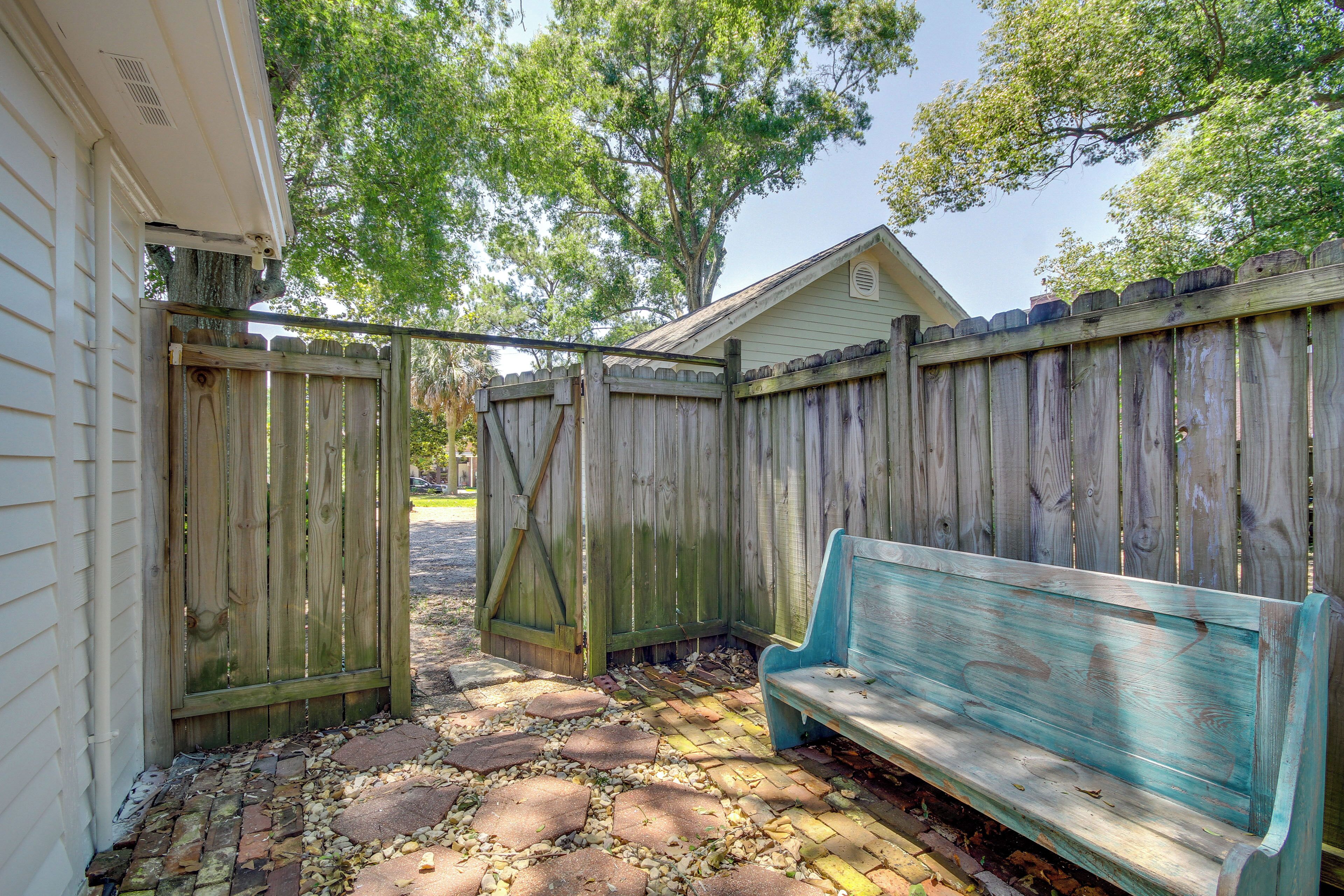 A wooden fence, a bench, and a paved walkway leading to a house.