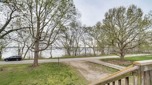A park with a wooden deck, a dirt path, and a car parked by the road.