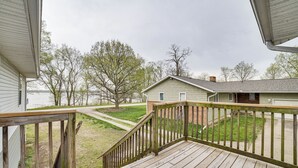 A wooden deck with a view of a house and a lake.