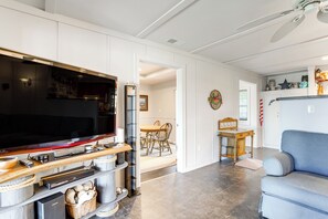 A modern living room with a flat-screen TV, wooden entertainment unit, and a blue sofa. - Waterfront Maryland Retreat w/ Dock & Bay View! (Deal Island)