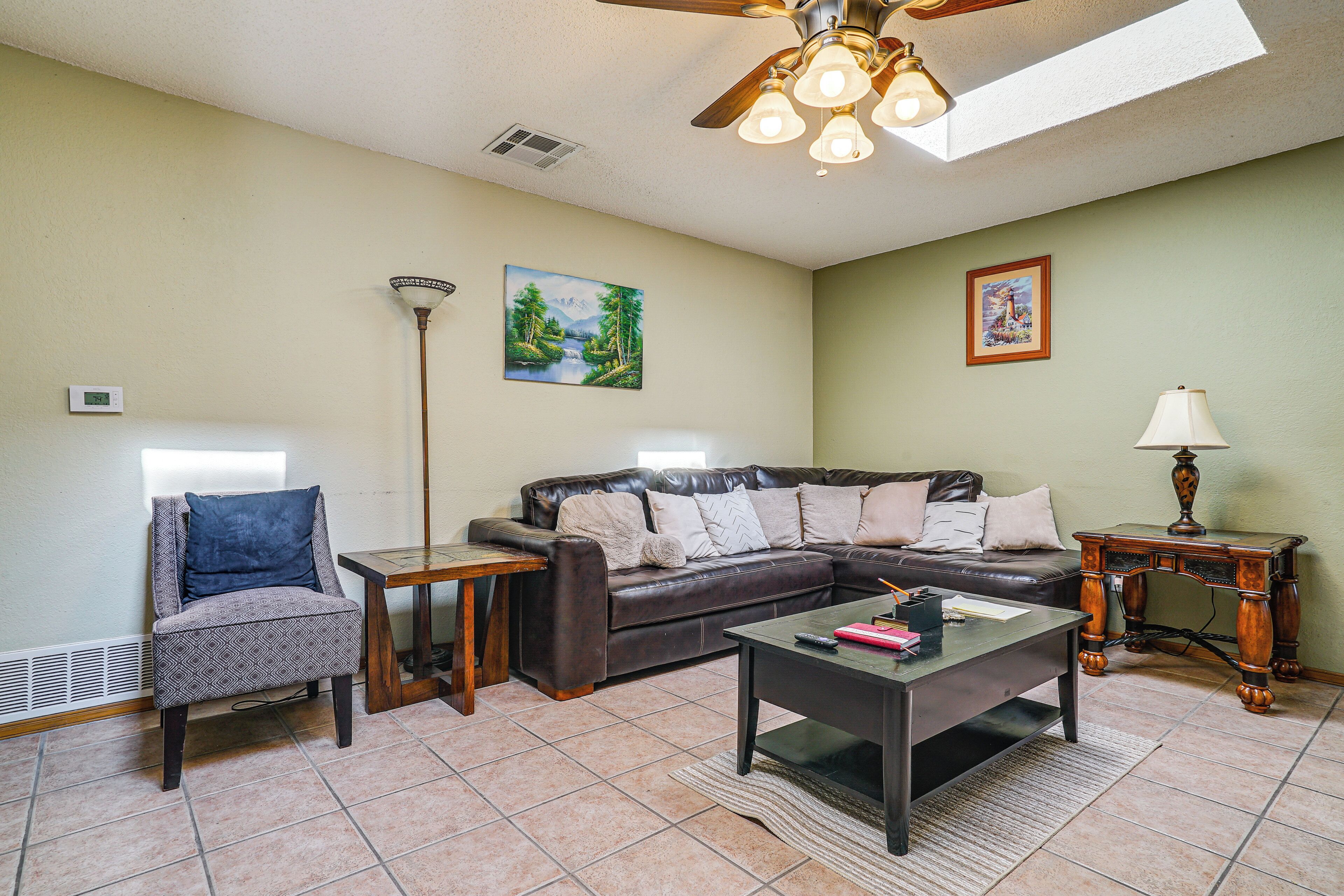 A living room with a sectional sofa, a coffee table, a side table, a floor lamp, and artwork on the walls.