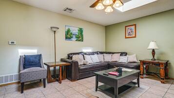 A living room with a sectional sofa, a coffee table, a side table, a floor lamp, and artwork on the walls.