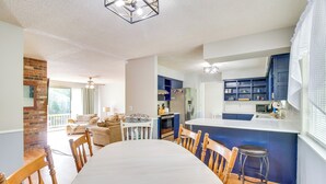 Ett modernt kök med en central köksö, en matplats med ett stort bord och stolar samt ett mysigt vardagsrum med en öppen spis och en soffa.