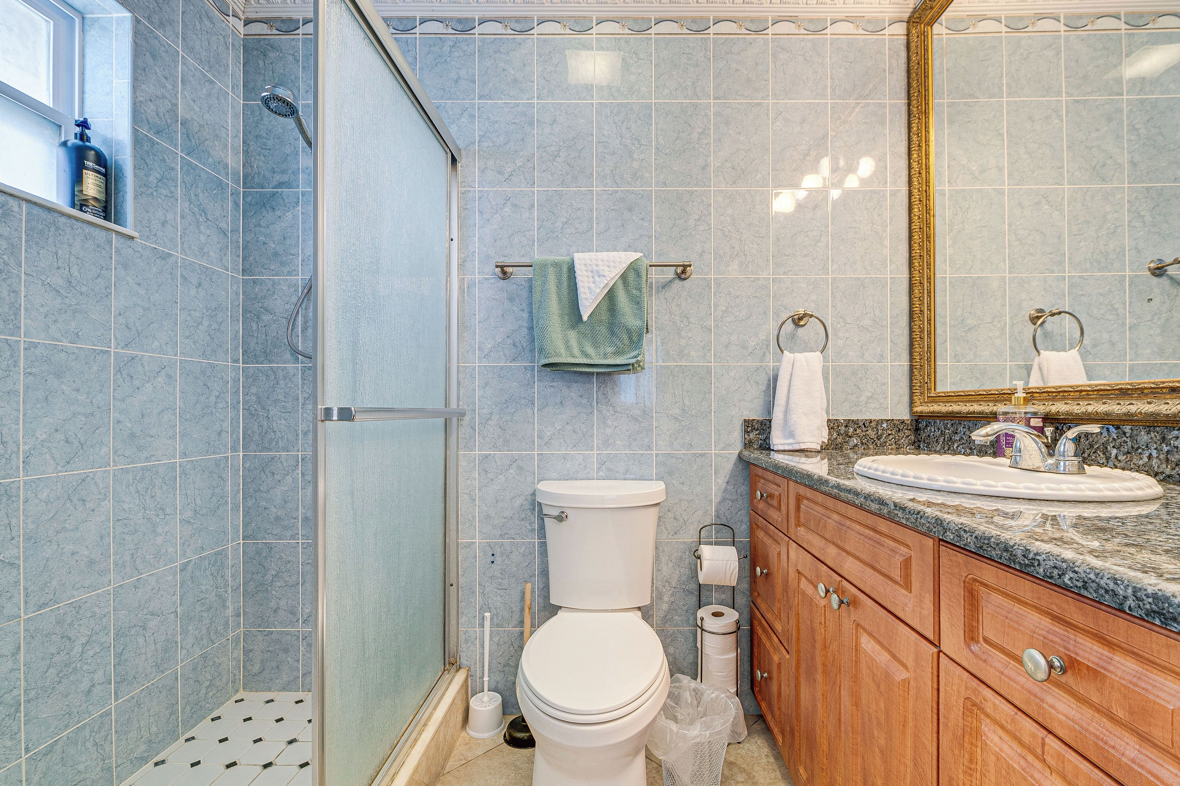 A bathroom with a shower, toilet, sink, and vanity.