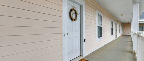A corridor with a white door, a doormat, and a wreath on the door.