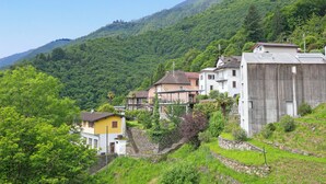 Un pueblo en una ladera con casas tradicionales, una escalera de piedra y abundante vegetación.