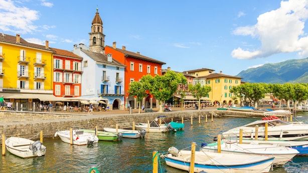 Un muelle con edificios coloridos, una torre de iglesia y barcos amarrados a la orilla.