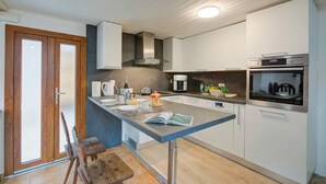 Una cocina moderna con una isla central, horno integrado y armarios blancos.