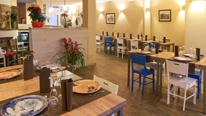 Un comedor con varias mesas y sillas, algunas con platos y cubiertos, y algunos maceteros.