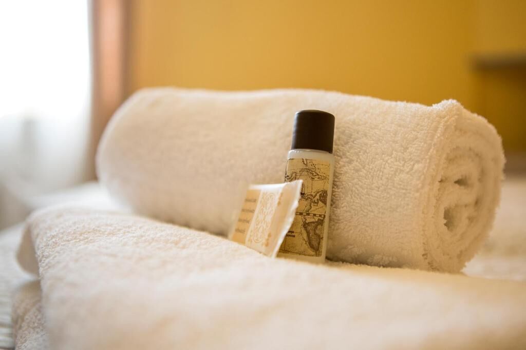 Une serviette blanche roulée, avec une bouteille de lotion et un petit paquet posé dessus.