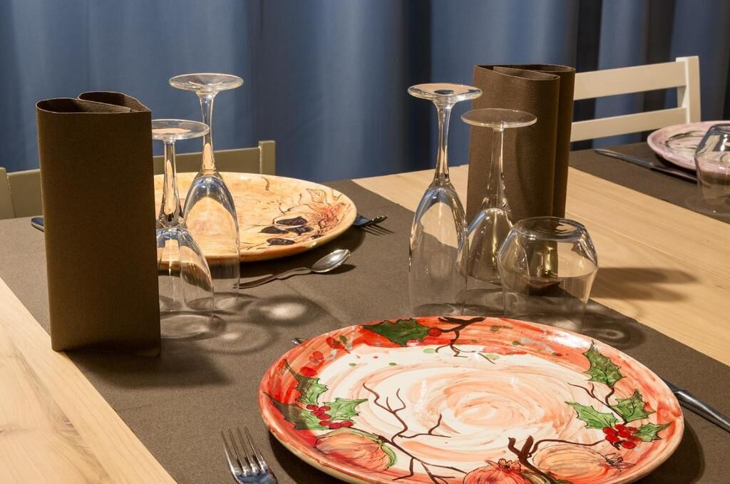 A dining table set with a floral plate, wine glasses, and a menu stand.