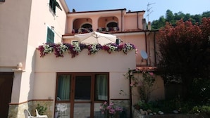 Un edificio con balcón decorado con flores, una puerta y una ventana.