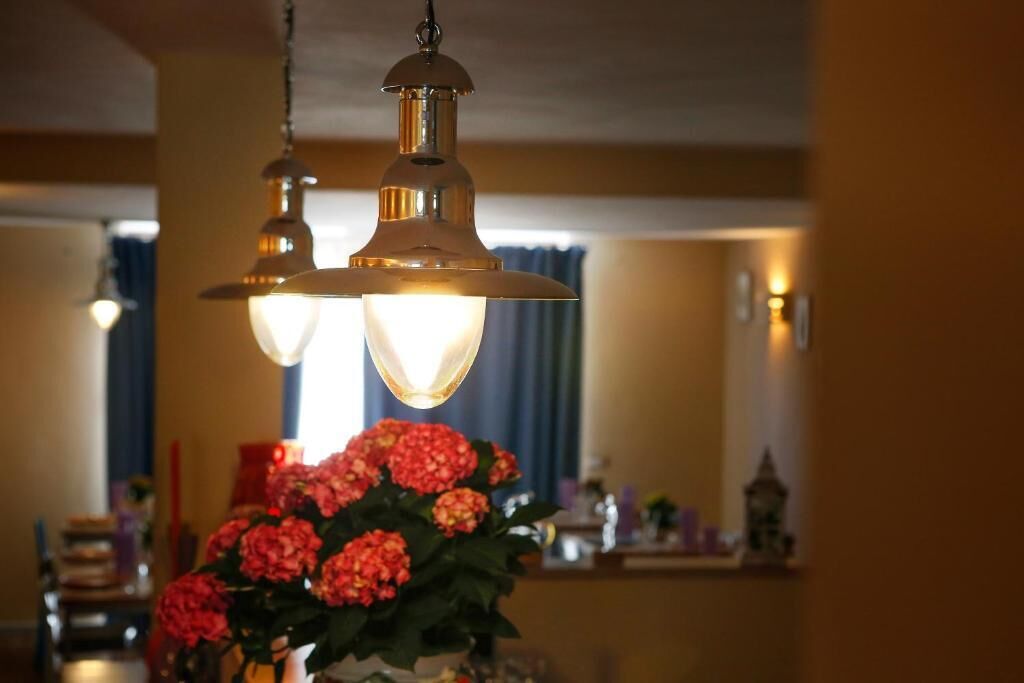 A dining area with a chandelier and a vase of flowers.