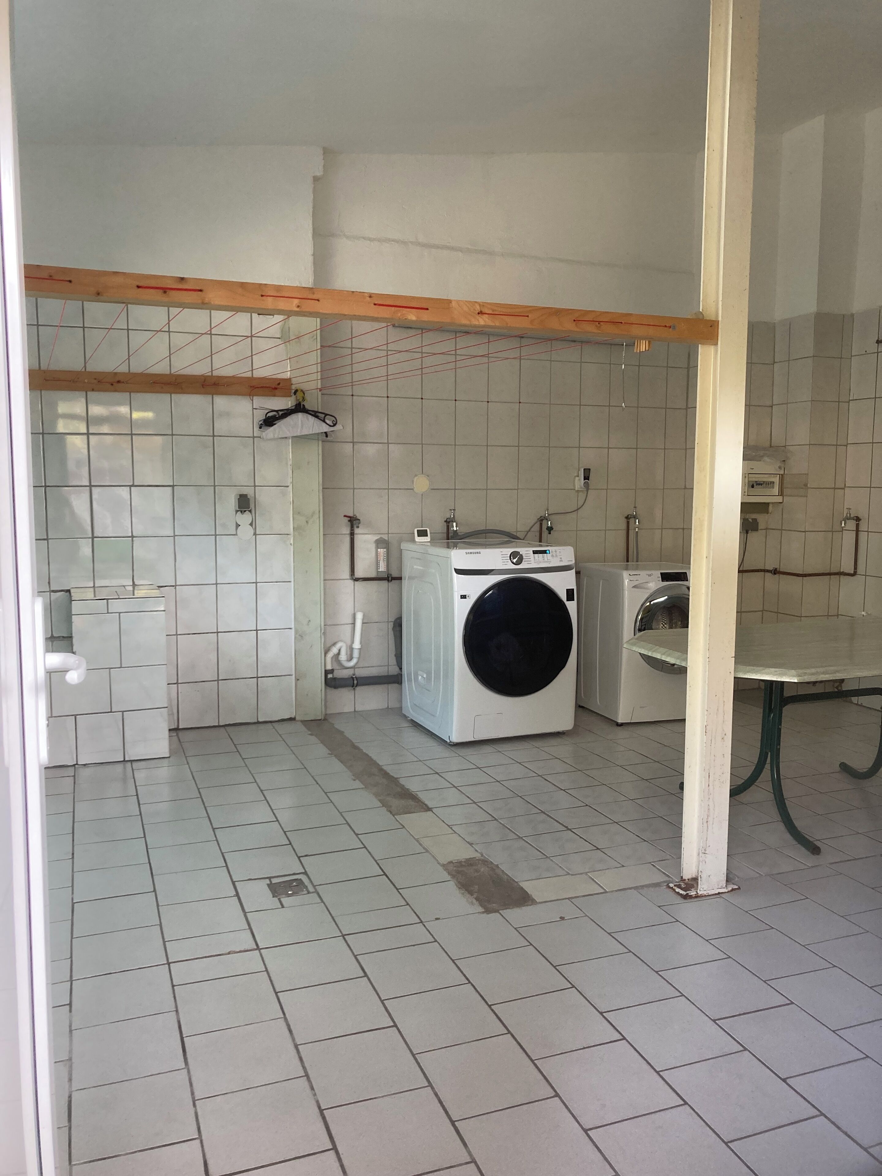 Una sala de bugaderia amb dues rentadores, un rentatrapets i un sòl de rajoles.