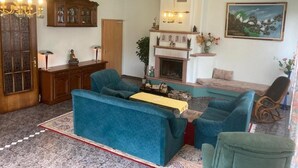 A living room with a fireplace, blue sofas, a wooden cabinet, and a painting on the wall. - Immensee III Apartment with lake view surrounded by forest (Ronshausen)