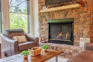 A cozy living room with a stone fireplace, leather sofa, and a wooden coffee table.