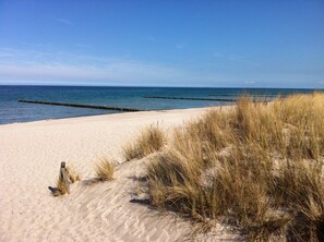En sandstrand med klitter og en klar blå himmel.