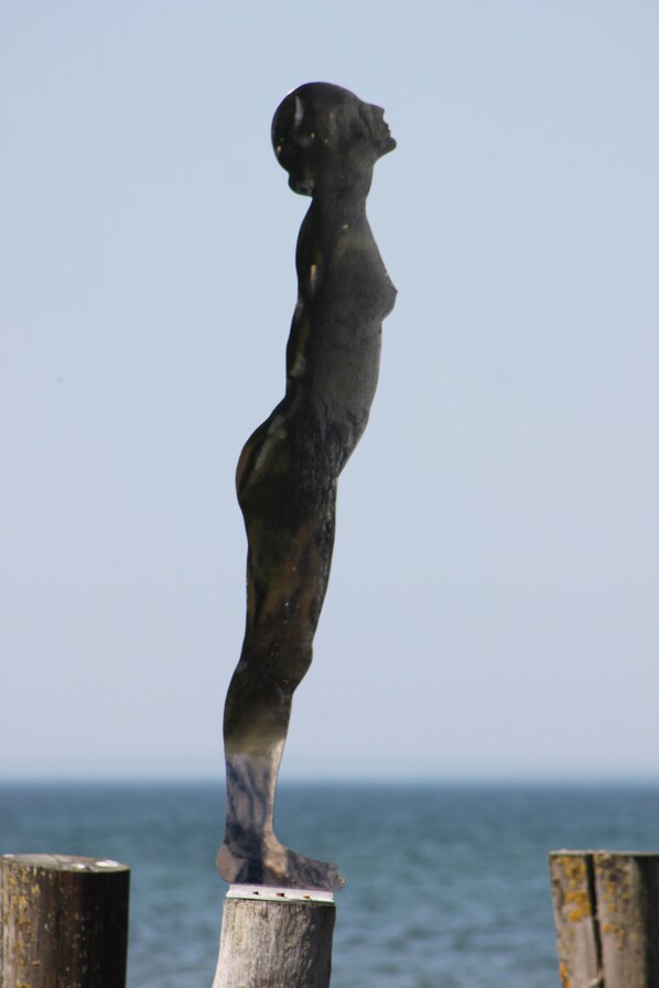 A statue of a child standing on a wooden post by the sea. - Zeit zur Erholung Ferienwohnung - 200m zum Strand (Zingst)