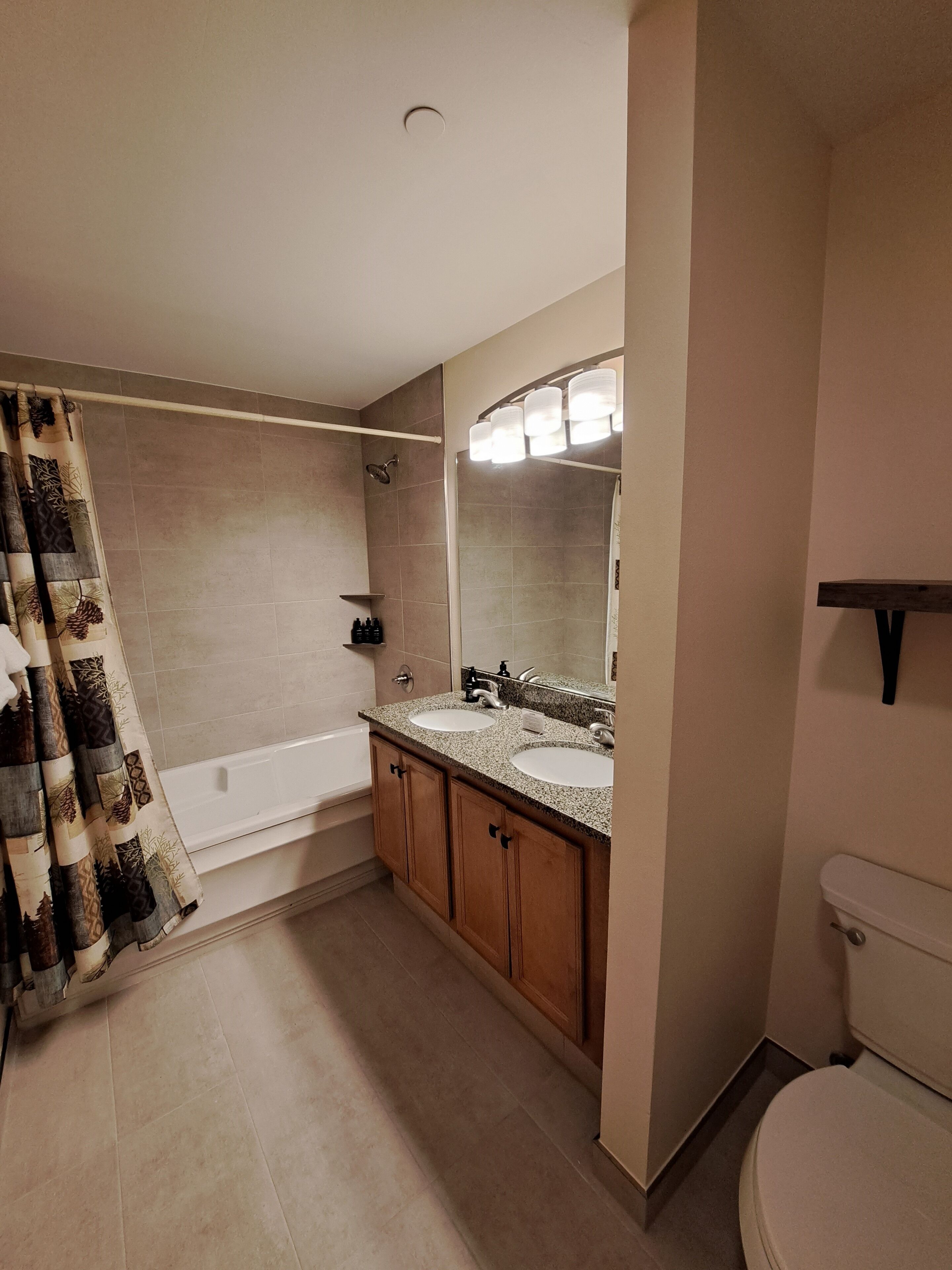 A bathroom with a bathtub, two sinks, a toilet, and a shower curtain.