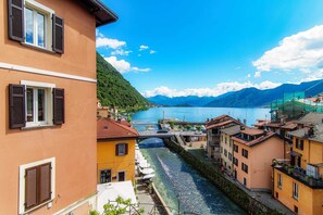 Un fiume con un ponte, edifici con balconi e montagne sullo sfondo.