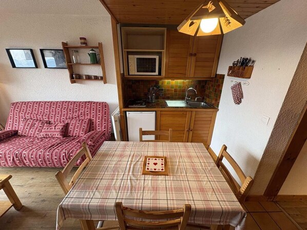 A compact living space with a kitchenette, a dining table, and a sofa.