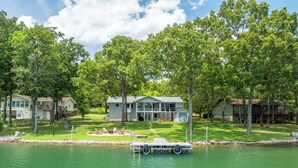 Une propriété au bord du lac comprenant une grande maison, un quai et un bateau.