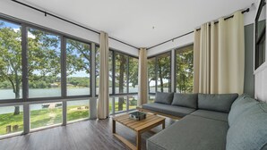 Un salon moderne avec de grandes fenêtres, un canapé gris et une table basse en bois.