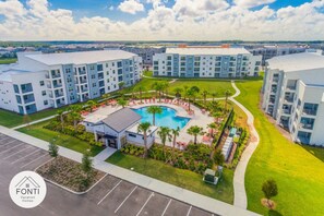A modern apartment complex with a central swimming pool, surrounded by well-maintained lawns and palm trees. - 3171-302 Resort Lake View Disney Universal Orlando (Kissimmee)