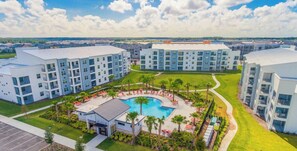 A modern apartment complex with a central swimming pool, surrounded by well-maintained lawns and palm trees. - 3171-302 Resort Lake View Disney Universal Orlando (Kissimmee)