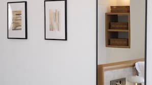 A mirror reflecting a room with a bed, bedside table, and wall-mounted shelves.