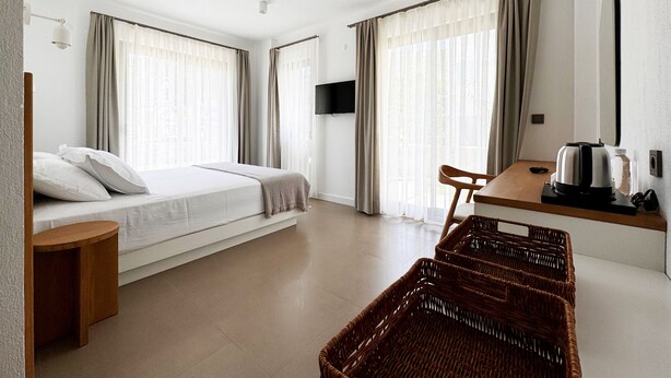 Una habitación de hotel con cama, escritorio, silla, televisor y una cesta de mimbre.