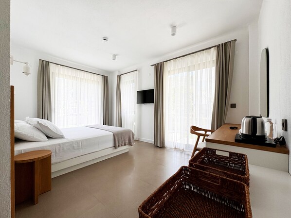 Een hotelkamer met een bed, een bureau, een stoel, een televisie en een rieten mand.