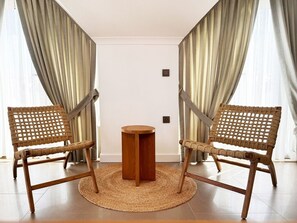 A room with two wicker chairs, a small wooden table, and a woven rug. - VİLLA KANTARLI (Datça)