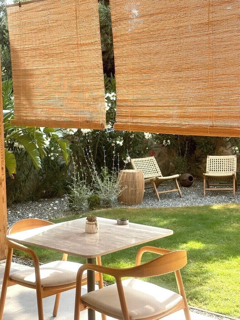 An outdoor seating area with a round table and two chairs, surrounded by a woven privacy screen.
