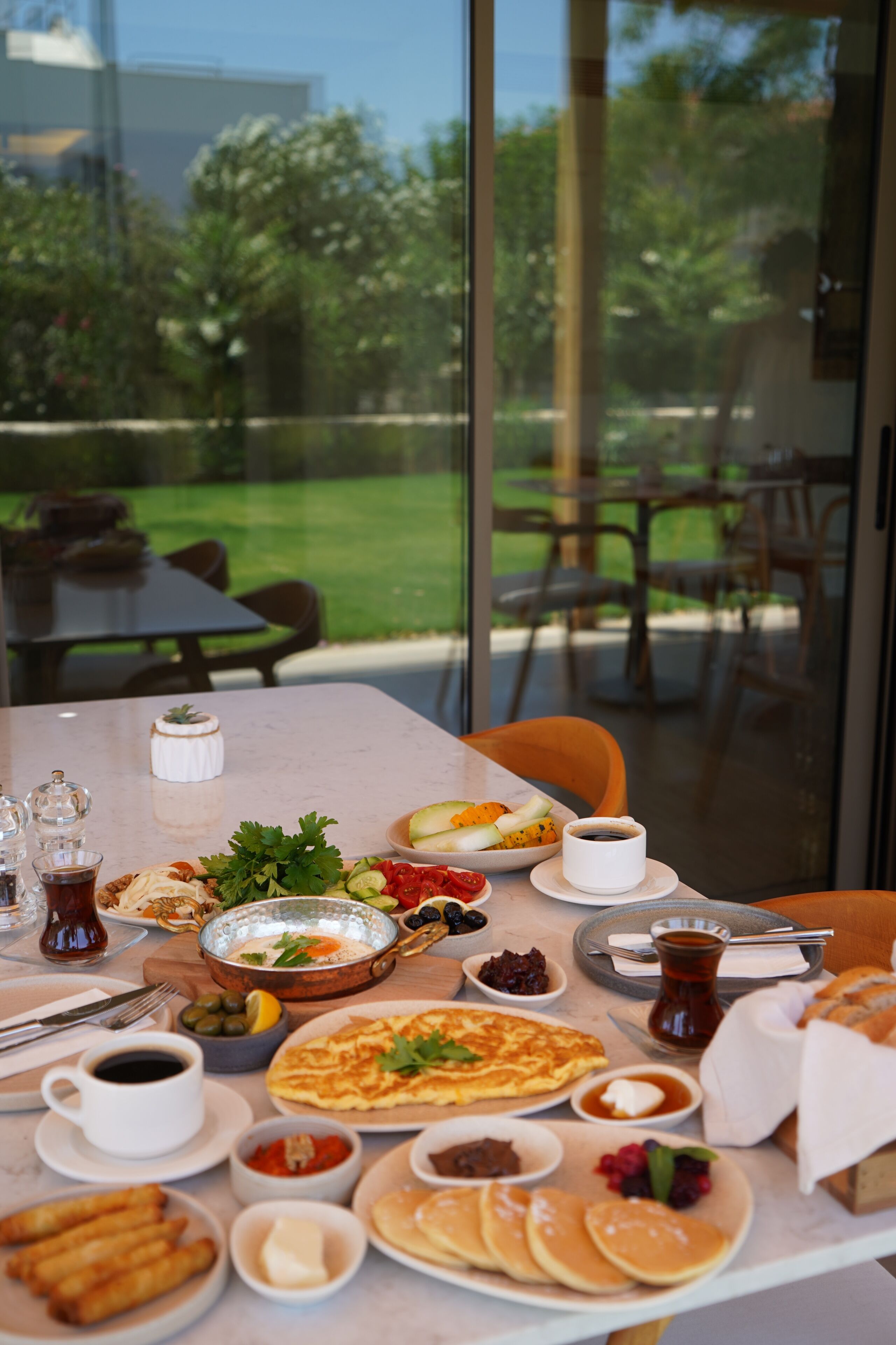 A dining table set with various dishes, including pancakes, a bowl of soup, and a plate of vegetables.