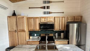 A kitchen with wooden cabinets, a stainless steel refrigerator, a microwave, and a sink.
