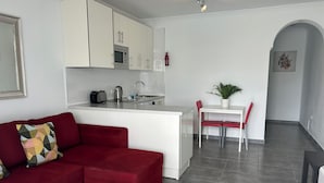 A compact living space with a kitchenette, a dining area, and a red sofa. - Cozy 1 bedroom apartment on a popular complex (Puerto del Carmen)
