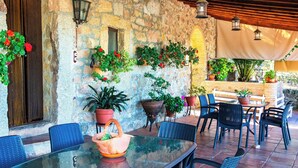 An outdoor patio with a stone wall, wooden ceiling, and potted plants. - Casa Rural Obejuelo. Balcón de los Pedroches (VILLANUEVA DE CÓRDOBA)