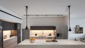 Una cucina moderna con una grande isola, elettrodomestici in acciaio inossidabile e illuminazione a sospensione.