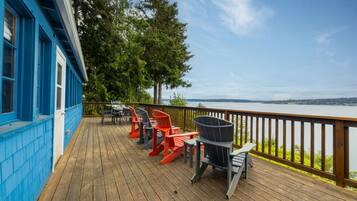Une terrasse en bois avec des sièges extérieurs et une vue sur un plan d’eau.
