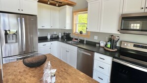 Une cuisine moderne avec des armoires blanches, des appareils en acier inoxydable et un plan de travail en bois.