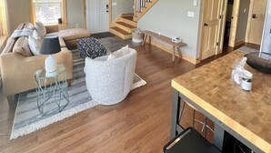 Un vaste espace de vie doté d’un plafond en bois, d’un escalier et d’un coin cuisine.