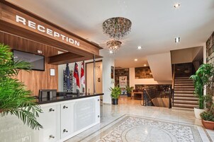 Un área de recepción con un mostrador de madera, una araña y una escalera que sube al piso superior.