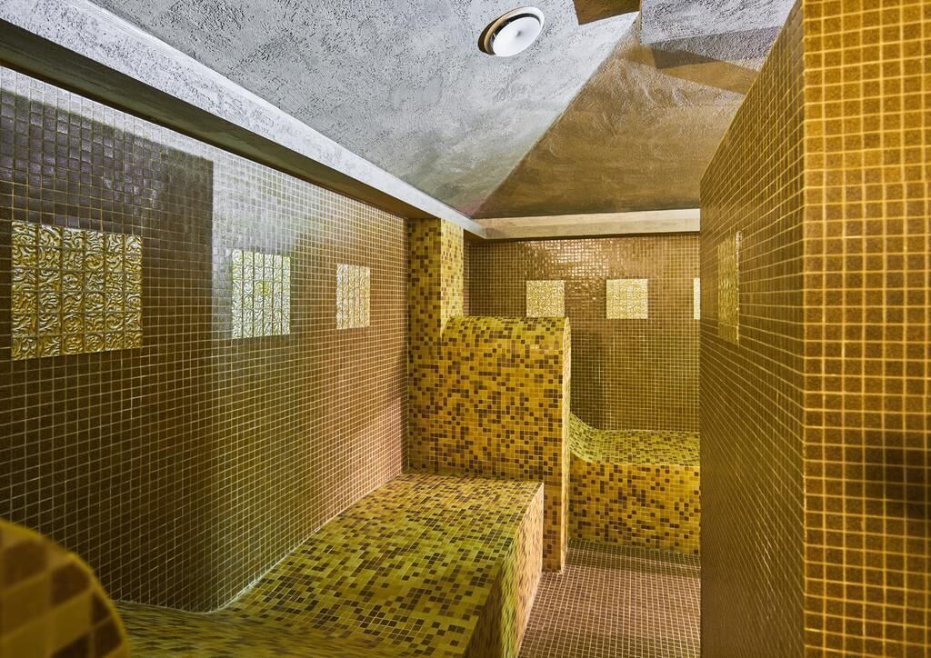 Casa de banho com paredes em mosaico e teto com iluminação embutida.