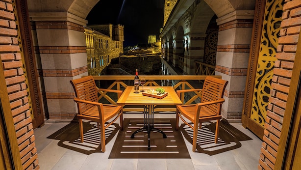 A balcony with a table and two chairs, overlooking a historic cityscape at night. - Hotel Gino Wellness Rabath (Akhaltsikhe)