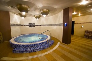 Un hidromasaje amplio en el interior, con suelo de mosaicos y barandilla de metal.