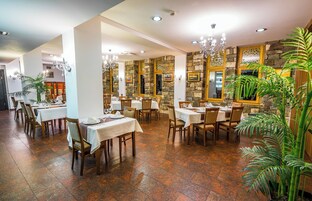 Un restaurante con varias mesas y sillas, paredes de piedra y un candelabro.